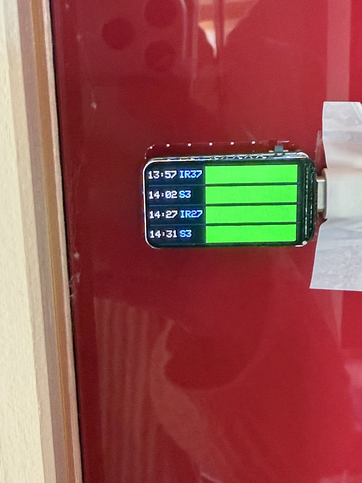 Swiss Transit Tracker board mounted on a red board with a bright green departure display